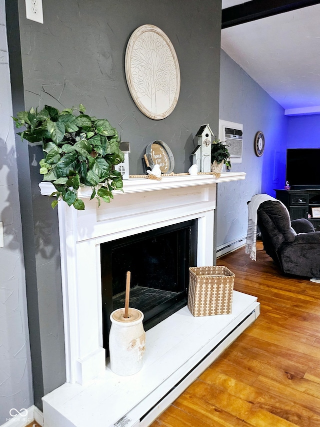 402 W Black Foot Trl, Greensburg, IN 47240 - detailed view of wood finished floors, a fireplace with raised hearth, baseboard heating, and a wall unit AC