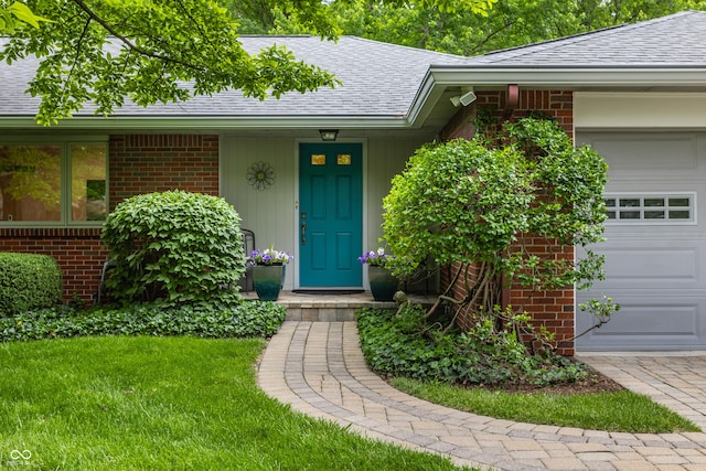 8905 Washington Blvd W Drive, Indianapolis, IN 46240 - doorway to property with an attached garage, roof with shingles, brick siding, and a yard