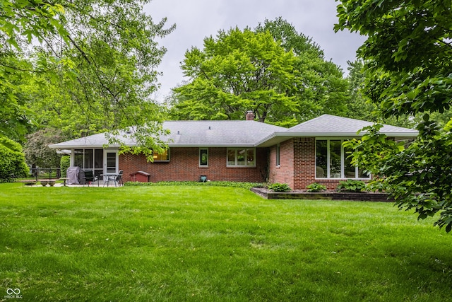 8905 Washington Blvd W Drive, Indianapolis, IN 46240 - rear view of property featuring a sunroom, brick siding, a lawn, and a chimney