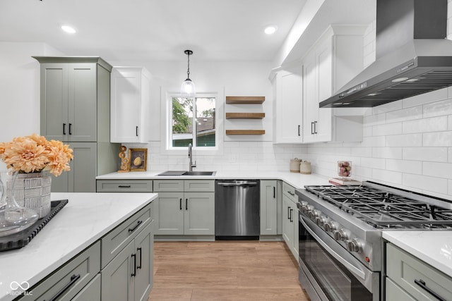 1027 Hosbrook St, Indianapolis, IN 46203 - kitchen featuring appliances with stainless steel finishes, wall chimney range hood, a sink, decorative backsplash, and decorative light fixtures