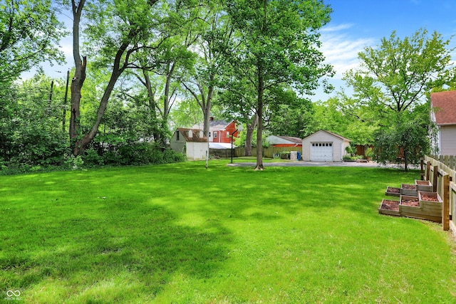 1725 W 53rd St, Indianapolis, IN 46228 - view of yard with an outdoor structure, a garage, a garden, and asphalt driveway