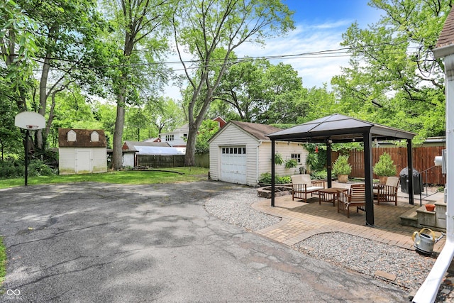 1725 W 53rd St, Indianapolis, IN 46228 - view of patio with a gazebo, asphalt driveway, an outdoor hangout area, area for grilling, and a detached garage