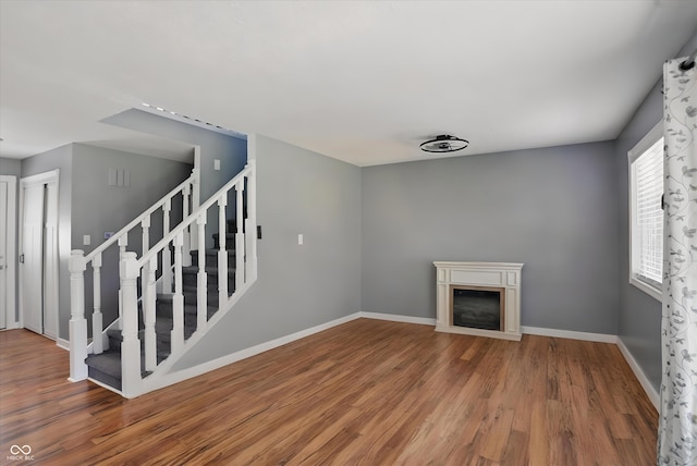 1240 Stringtown Pike, Cicero, IN 46034 - unfurnished living room featuring wood finished floors, a glass covered fireplace, stairs, and baseboards