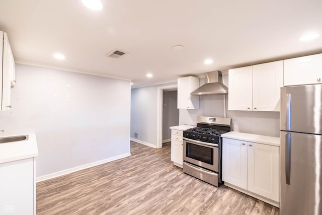5002 E Washington St, Indianapolis, IN 46201 - kitchen with appliances with stainless steel finishes, wall chimney exhaust hood, white cabinetry, light countertops, and light wood-style flooring