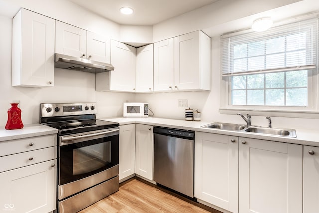 5002 E Washington St, Indianapolis, IN 46201 - kitchen with stainless steel appliances, under cabinet range hood, light countertops, white cabinets, and light wood-style floors