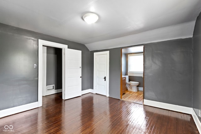 1021 W 37th St, Indianapolis, IN 46208 - unfurnished bedroom featuring vaulted ceiling, hardwood / wood-style floors, baseboards, and connected bathroom