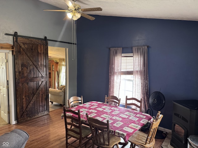 2208 S F St, Elwood, IN 46036 - dining area featuring a barn door, ceiling fan, vaulted ceiling, a textured ceiling, and wood finished floors