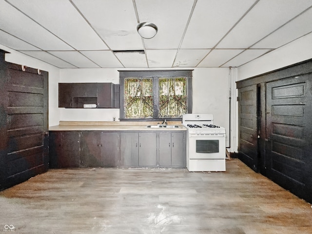 526 N Centennial St, Indianapolis, IN 46222 - kitchen with gas range gas stove, light wood-style floors, light countertops, a sink, and a drop ceiling