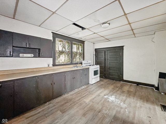 526 N Centennial St, Indianapolis, IN 46222 - kitchen featuring white range with gas cooktop, a paneled ceiling, light wood-style flooring, light countertops, and baseboards
