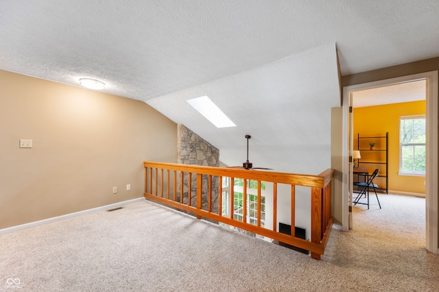 6263 Behner Way, Indianapolis, IN 46250 - corridor with a skylight, carpet flooring, a textured ceiling, baseboards, and lofted ceiling