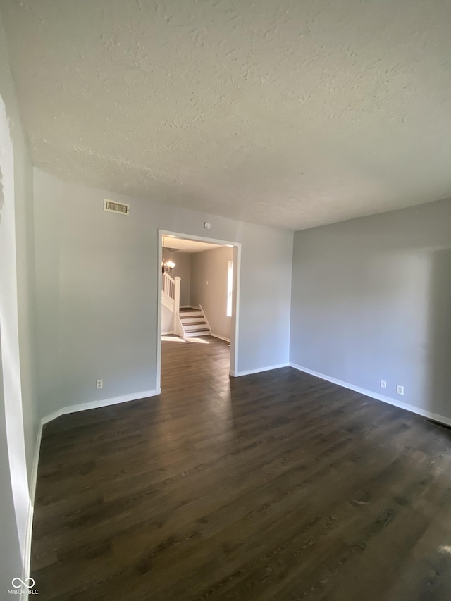 653 Birch Ave, Indianapolis, IN 46221 - spare room with a textured ceiling, dark wood-type flooring, stairway, and baseboards