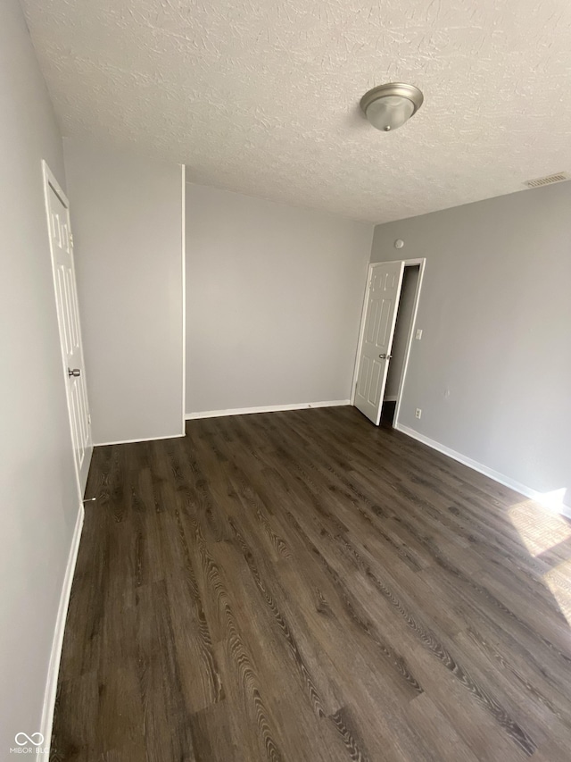 653 Birch Ave, Indianapolis, IN 46221 - spare room with a textured ceiling, dark wood-type flooring, and baseboards