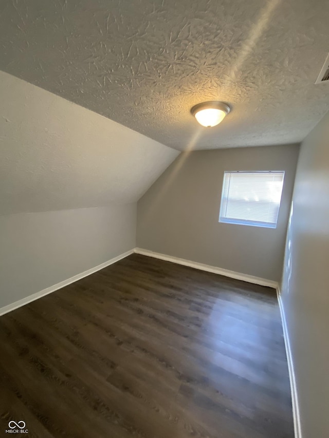 653 Birch Ave, Indianapolis, IN 46221 - additional living space with dark wood finished floors, vaulted ceiling, baseboards, and a textured ceiling