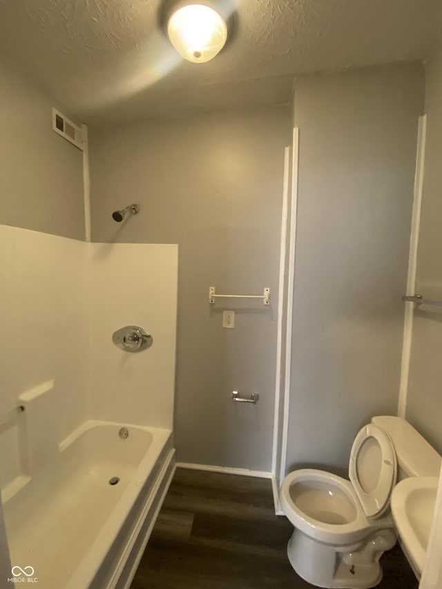 653 Birch Ave, Indianapolis, IN 46221 - bathroom with wood finished floors, toilet, a textured ceiling, baseboards, and shower / tub combination
