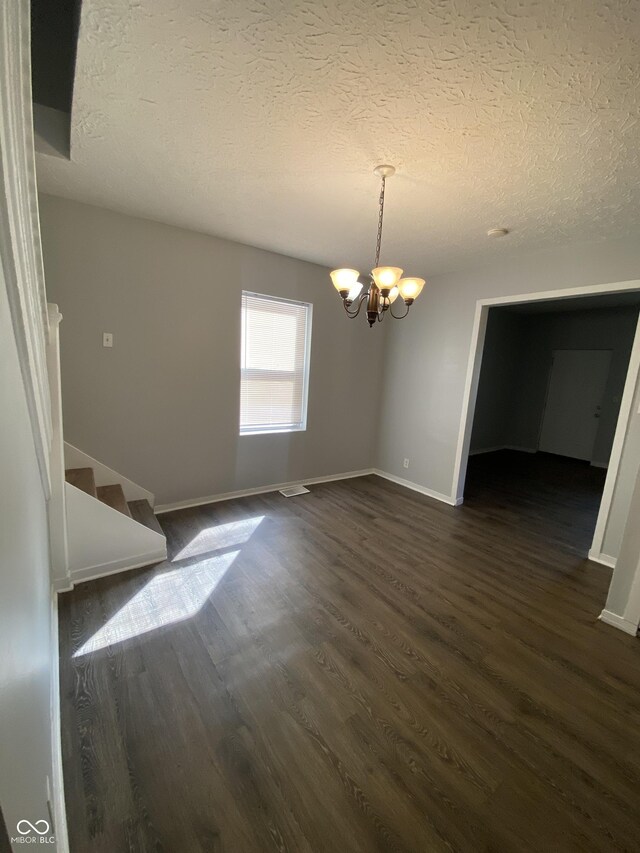 653 Birch Ave, Indianapolis, IN 46221 - unfurnished dining area with a chandelier, dark wood finished floors, a textured ceiling, stairs, and baseboards