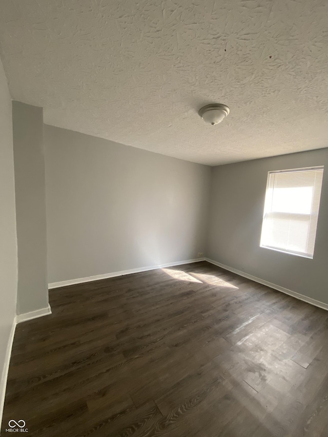 653 Birch Ave, Indianapolis, IN 46221 - empty room with dark wood finished floors, baseboards, and a textured ceiling