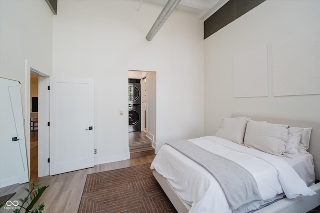 611 N Park Ave Unit 108, Indianapolis, IN 46204 - bedroom featuring stacked washer / dryer, a towering ceiling, and wood finished floors