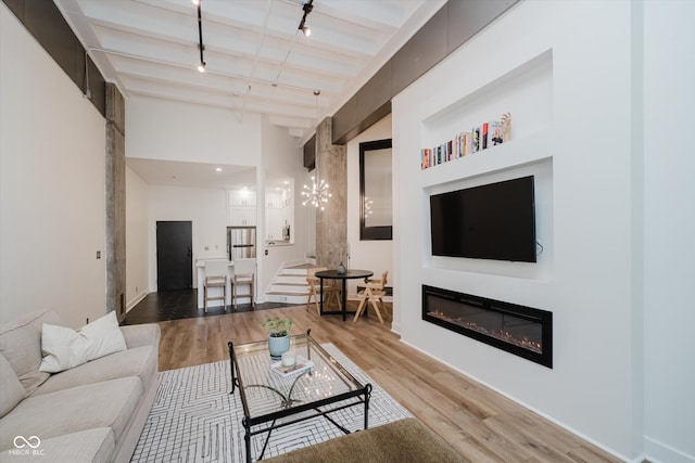 611 N Park Ave Unit 108, Indianapolis, IN 46204 - living area with wood finished floors, a glass covered fireplace, rail lighting, beamed ceiling, and stairs