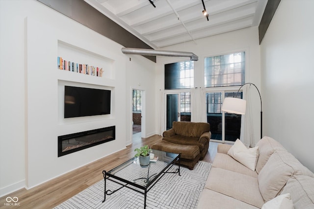 611 N Park Ave Unit 108, Indianapolis, IN 46204 - living room with beam ceiling, a glass covered fireplace, wood finished floors, baseboards, and a high ceiling