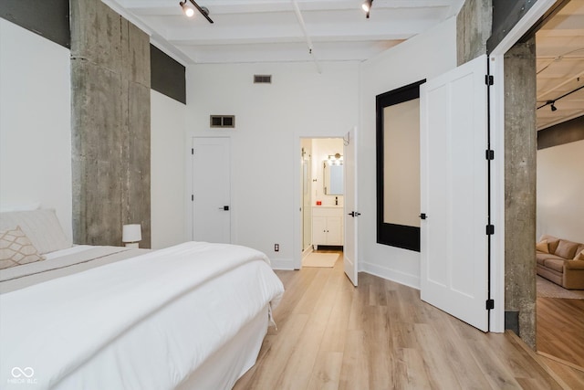 611 N Park Ave Unit 108, Indianapolis, IN 46204 - bedroom featuring rail lighting, light wood-type flooring, and connected bathroom