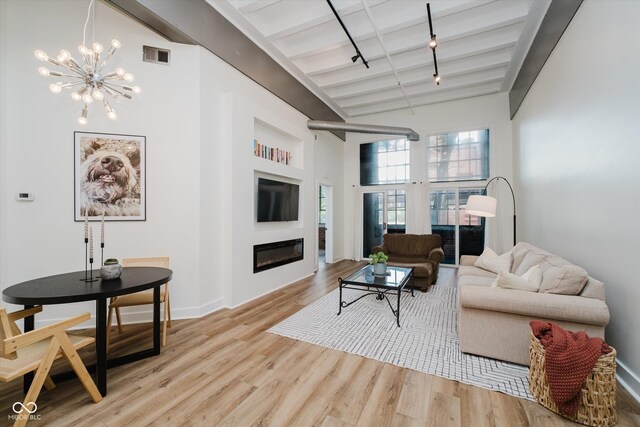 611 N Park Ave Unit 108, Indianapolis, IN 46204 - living room featuring beam ceiling, a glass covered fireplace, wood finished floors, a chandelier, and baseboards