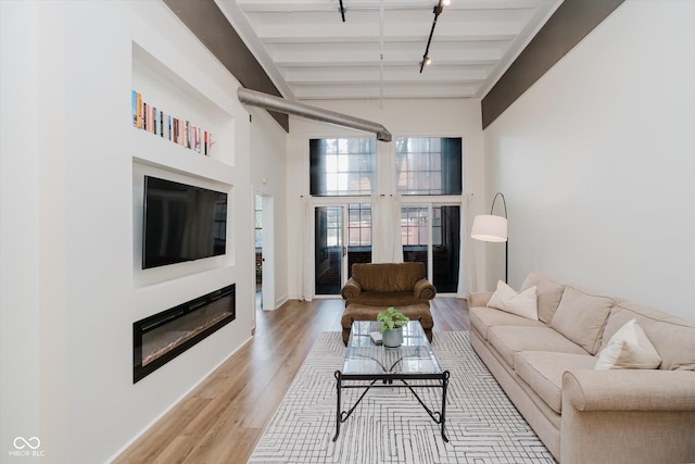 611 N Park Ave Unit 108, Indianapolis, IN 46204 - living area featuring beam ceiling, a glass covered fireplace, light wood-style flooring, high vaulted ceiling, and baseboards