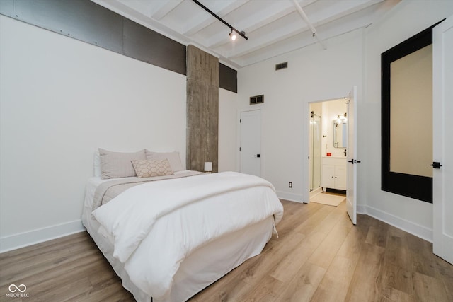 611 N Park Ave Unit 108, Indianapolis, IN 46204 - bedroom featuring a towering ceiling, light wood-style flooring, track lighting, baseboards, and beamed ceiling