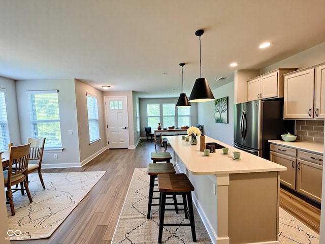 17399 Dovehouse Ln, Westfield, IN 46074 - kitchen with freestanding refrigerator, light wood-style flooring, light countertops, a kitchen island with sink, and baseboards