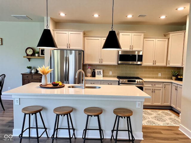17399 Dovehouse Ln, Westfield, IN 46074 - kitchen featuring appliances with stainless steel finishes, a sink, a breakfast bar, light wood-style floors, and decorative light fixtures