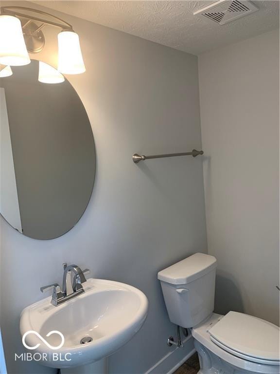 17399 Dovehouse Ln, Westfield, IN 46074 - half bathroom featuring a sink, toilet, and a textured ceiling