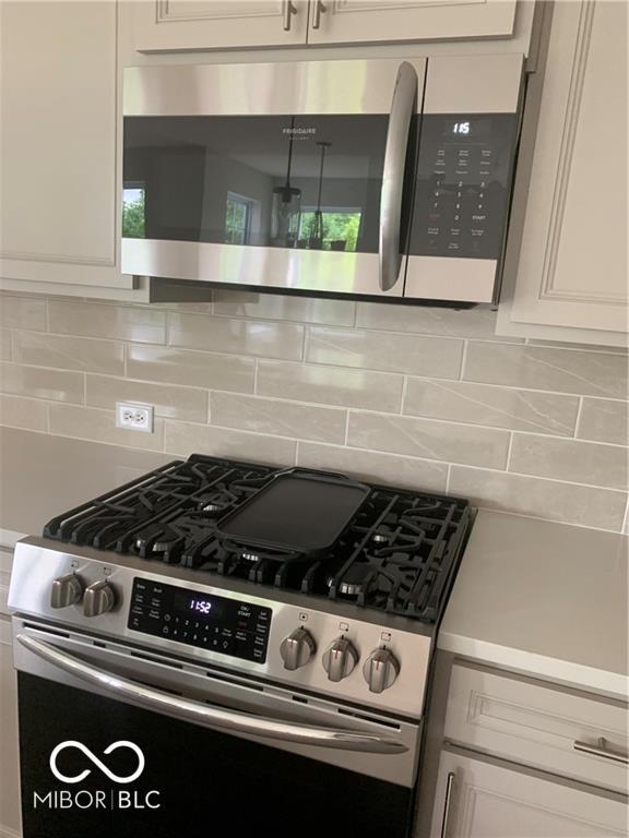 17399 Dovehouse Ln, Westfield, IN 46074 - kitchen with stainless steel appliances, tasteful backsplash, white cabinets, and light countertops
