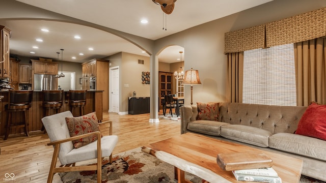 12539 Pebblepointe Pass, Carmel, IN 46033 - living area with arched walkways, light wood-style floors, recessed lighting, and a chandelier