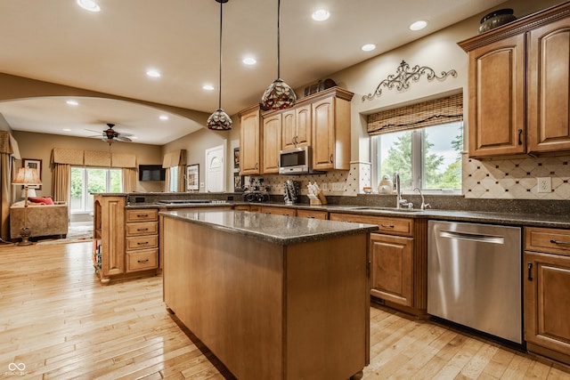 12539 Pebblepointe Pass, Carmel, IN 46033 - kitchen with appliances with stainless steel finishes, a sink, arched walkways, a center island, and light wood-style floors