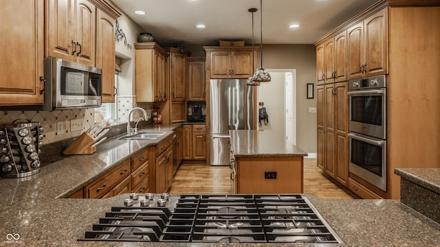 12539 Pebblepointe Pass, Carmel, IN 46033 - kitchen featuring appliances with stainless steel finishes, a sink, a center island, dark stone countertops, and backsplash