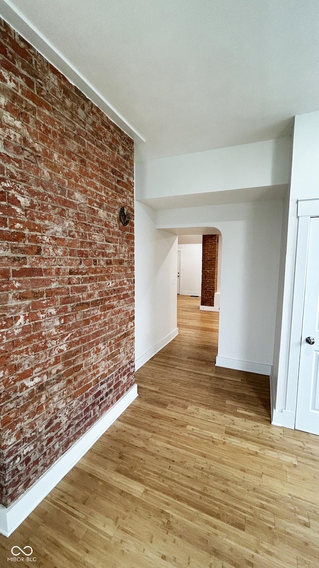 909 N Temple Ave, Indianapolis, IN 46201 - corridor with baseboards, light wood-type flooring, arched walkways, and brick wall