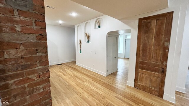 909 N Temple Ave, Indianapolis, IN 46201 - unfurnished room featuring light wood-style flooring, arched walkways, baseboards, brick wall, and recessed lighting