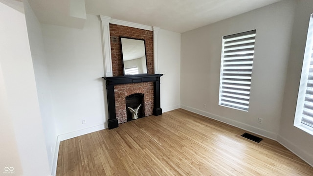 909 N Temple Ave, Indianapolis, IN 46201 - unfurnished living room with a fireplace, light wood-type flooring, and baseboards