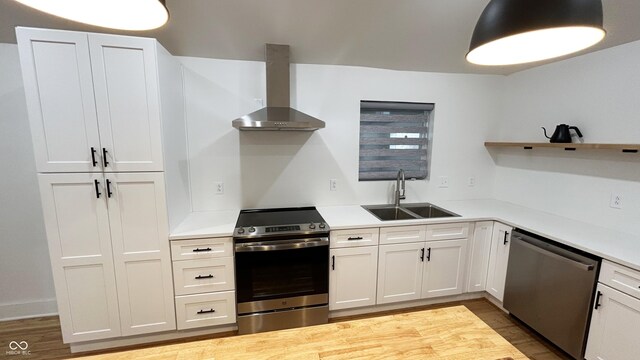 909 N Temple Ave, Indianapolis, IN 46201 - kitchen with wall chimney range hood, stainless steel appliances, a sink, open shelves, and wood finished floors