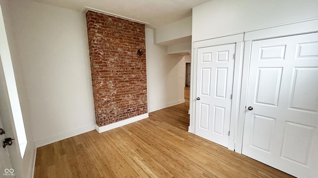 909 N Temple Ave, Indianapolis, IN 46201 - unfurnished bedroom featuring baseboards, light wood-style flooring, a closet, and brick wall