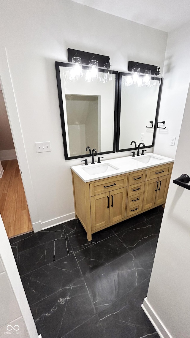 909 N Temple Ave, Indianapolis, IN 46201 - full bathroom with marble look tile flooring, double vanity, and baseboards