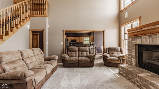 719 E New Rd, Greenfield, IN 46140 - living room featuring a towering ceiling, light carpet, a fireplace, and stairway