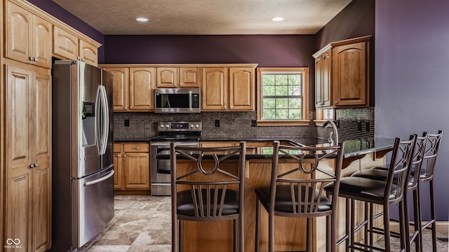 719 E New Rd, Greenfield, IN 46140 - kitchen with appliances with stainless steel finishes, a peninsula, decorative backsplash, a kitchen breakfast bar, and dark countertops