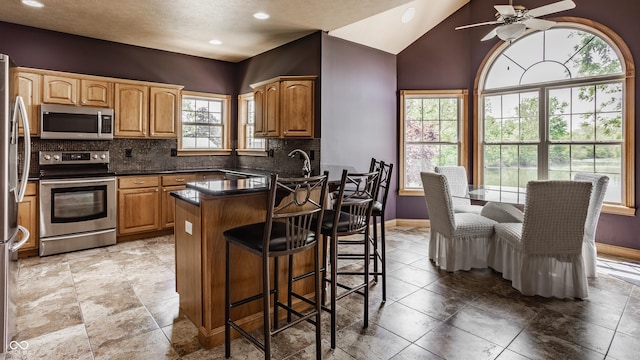 719 E New Rd, Greenfield, IN 46140 - kitchen featuring appliances with stainless steel finishes, baseboards, a peninsula, a breakfast bar area, and a ceiling fan