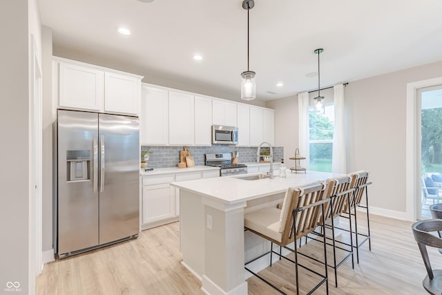 1085 Bevy Blvd, Danville, IN 46122 - kitchen with appliances with stainless steel finishes, a sink, light wood-style floors, tasteful backsplash, and a kitchen island with sink