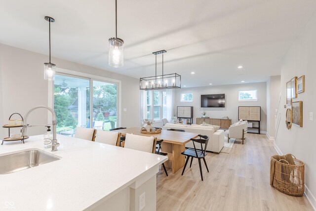 1085 Bevy Blvd, Danville, IN 46122 - kitchen featuring a sink, light wood-style floors, hanging light fixtures, light countertops, and baseboards