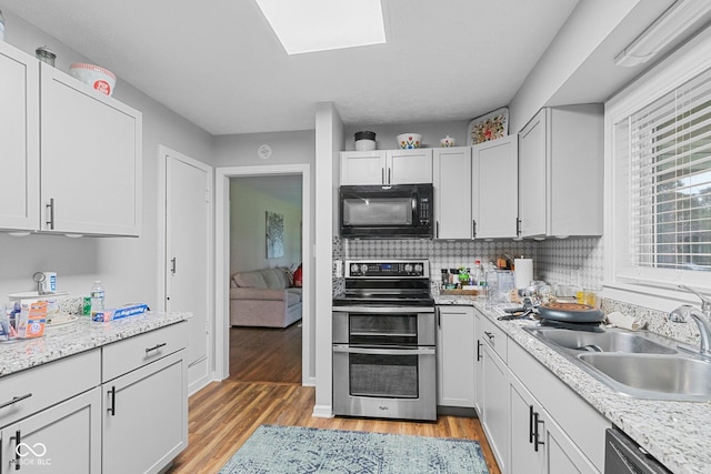 426 Tipton Ln, Columbus, IN 47201 - kitchen featuring black microwave, range with two ovens, a sink, and light wood-type flooring