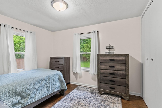 426 Tipton Ln, Columbus, IN 47201 - bedroom with multiple windows, baseboards, dark wood-type flooring, and a textured ceiling