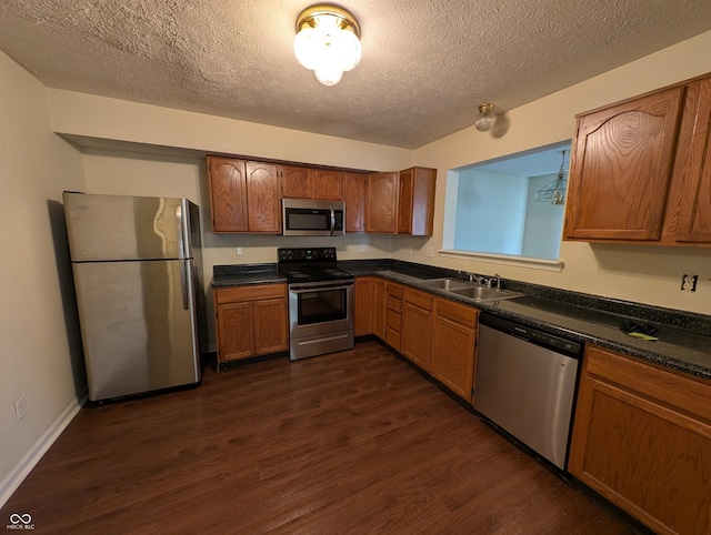 10722 Mistflower Way, Indianapolis, IN 46235 - kitchen with appliances with stainless steel finishes, a sink, dark wood-style floors, dark countertops, and a textured ceiling