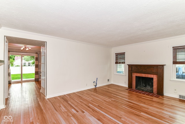 2526 Dell Zell Dr, Indianapolis, IN 46220 - unfurnished living room featuring crown molding, light wood-type flooring, a chandelier, a textured ceiling, and plenty of natural light