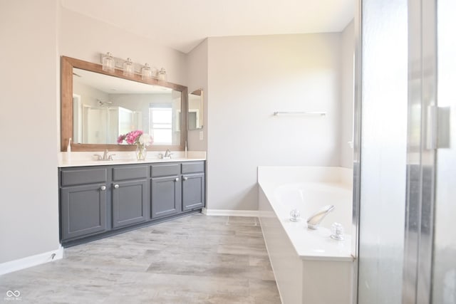 12677 Honors Dr, Carmel, IN 46033 - full bath featuring double vanity, a garden tub, wood finished floors, and baseboards